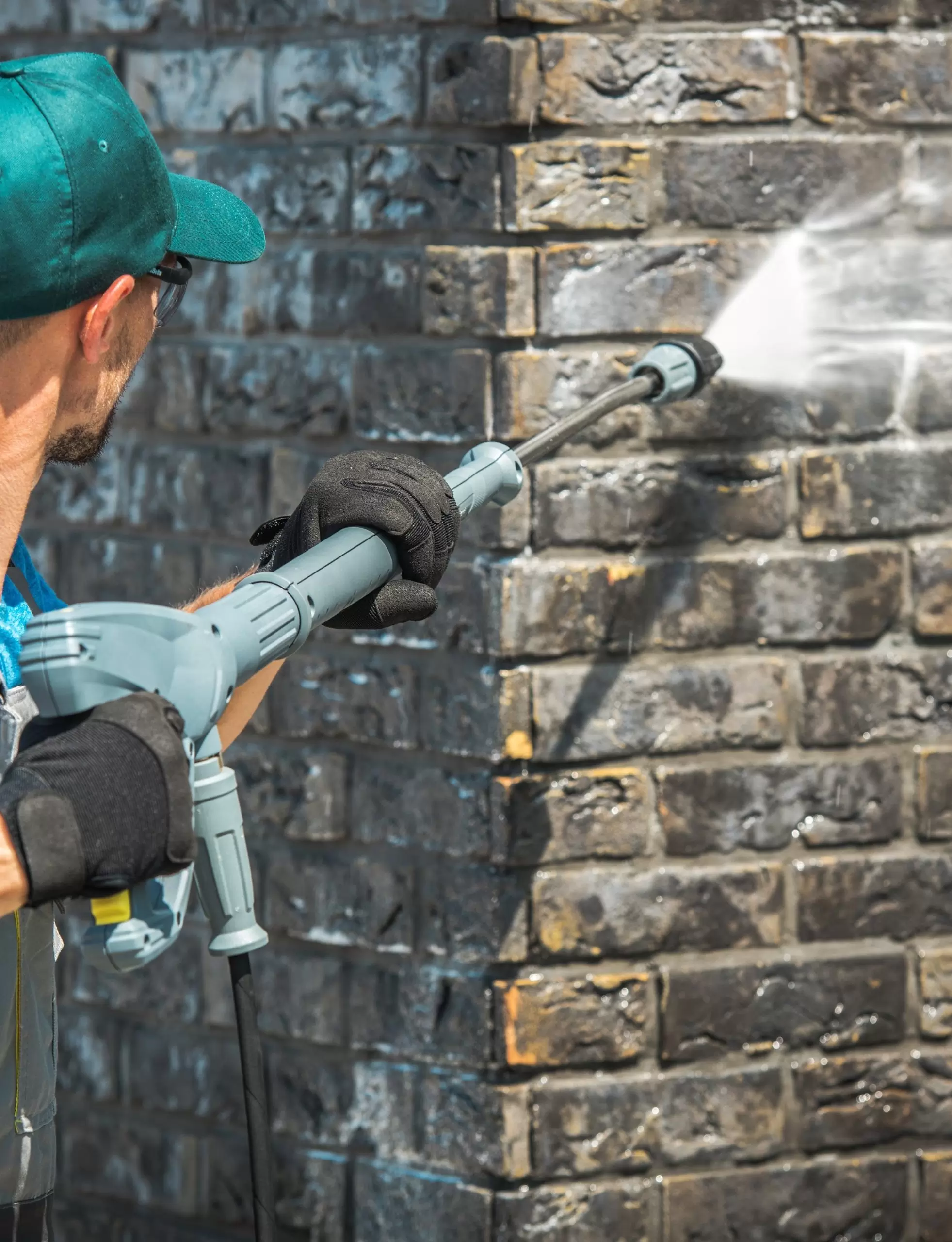 House Brick Wall Washing Using Pressure Washer. Caucasian Worker in His 30s.