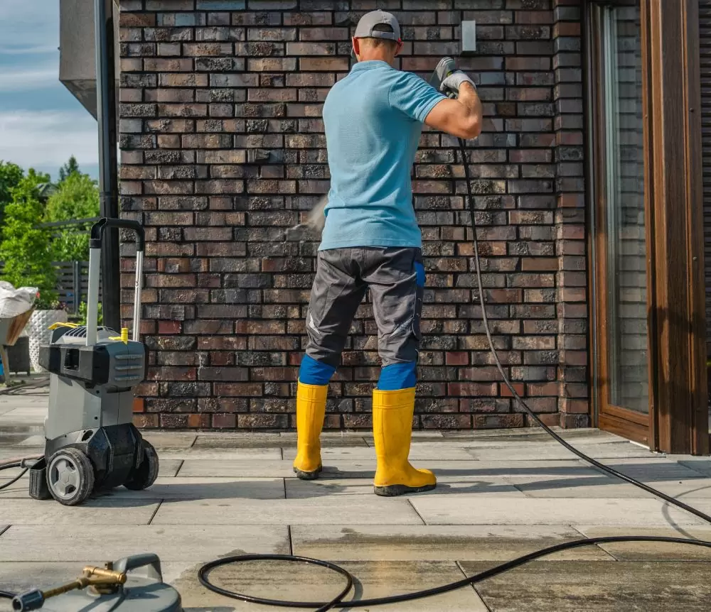 person-cleaning-exterior-wall-with-pressure-washer-sunny-day-residential-area sq (1)